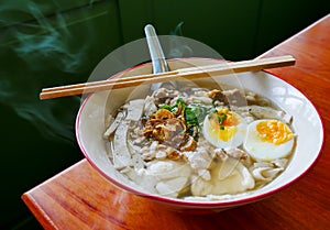Traditional chinese food in thailand by angle view, Local white noodle with steam in chicken soup, topping by pressed pork boiled