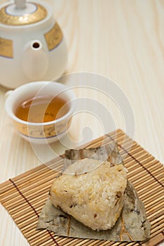 Traditional Chinese glutinous rice dumpling with cup of tea and teapot vertical