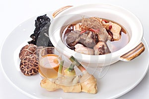 Traditional Chinese herbal soup with chicken and raw ingredients on the side