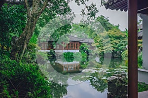 Traditional Chinese house by pond with reflection in water, in a Chinese garden, near West Lake, Hangzhou, China