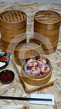 Traditional chinese steamed Chili Dim Sums or chili Shumai dimsum in bamboo steamer with sauce and chopsticks