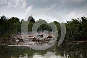 Traditional Chinese stone bridge across the lake lost in green t