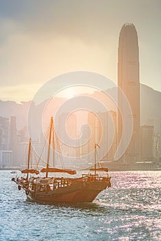 Traditional Chinese wooden sailing ship with red sails. Skyscrapers in downtown of Hong Kong are visible from Kowloon side
