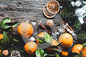Traditional Christmas background with fir tree, tangerines, cinnamon and natural snow on wooden background