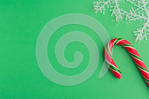 Traditional christmas caramel candy cane and snowflakes on a green background. Winter Holiday festive greeting card with copy