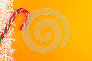 Traditional christmas caramel candy cane and snowflakes on a orange background. Winter Holiday festive greeting card with copy