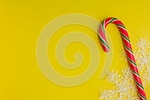 Traditional christmas caramel candy cane and snowflakes on a yellow background. Winter Holiday festive greeting card with copy