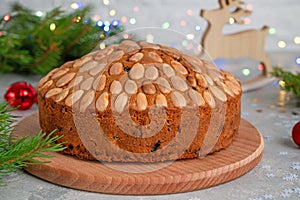 Traditional Christmas Dundee cake with dried fruits and almonds on a wooden board. Festive dessert