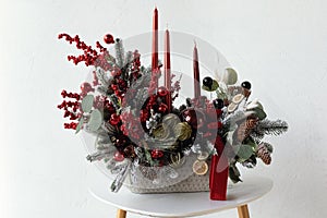 Traditional Christmas flower arrangement of green fir branches and red candles for a gift. New Year`s decor for the interior