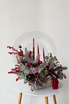 Traditional Christmas flower arrangement of green fir branches and red candles for a gift. New Year`s decor for the interior