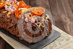 Traditional christmas fruit cake in chocolate glaze on wooden ba