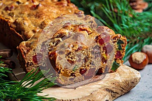 Traditional Christmas fruit cake on a wooden board in festive decoration, dark background