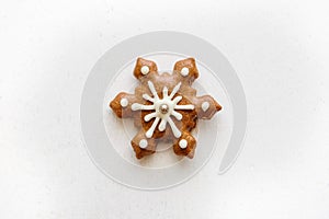 A traditional Christmas gingerbread cookie in the shape of a snowflake on a white background