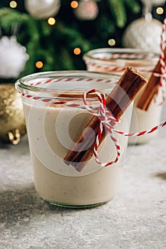 Traditional Christmas milk cocktail - Eggnog with cinnamon, served in two glasses on festive concrete background.