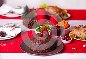 Traditional Christmas pudding with holly on top on a Christmas dinner