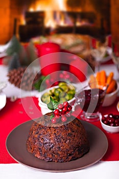 Traditional Christmas pudding with holly on top on a Christmas dinner.