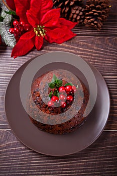 Traditional Christmas pudding with holly on top on the wooden background