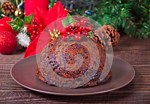 Traditional Christmas pudding with holly on top on the wooden background