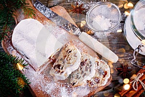 Traditional Christmas Stollen Fruit Cake on wooden background with Christmas Lights