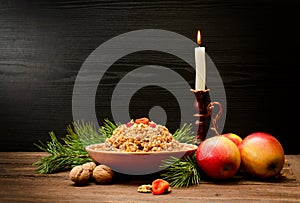 Traditional Christmas treat of the Slavs on Christmas eve kutia. Fir branch, apples, candle on wooden background