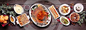 Traditional Christmas turkey dinner. Top view panoramic table scene on a dark wood banner background.