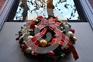 Traditional Christmas wreath under window with blur reflection