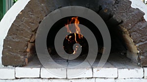 A traditional clay oven for cooking and baking pizza, with wood flame in the background.