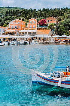 Traditional colorful Greek fishing boat in front of picturesque village, Greece