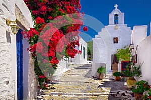 Traditional colorful mediterranean street with flowers and church, Cyclades, Greece