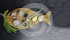 traditional cooking ingredients: lemon, garlic, olive oil, Himalayan salt, pepper, fresh herbs on black wooden background. Food