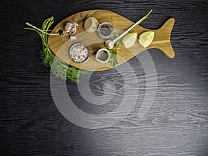 traditional cooking ingredients: lemon, garlic, olive oil, Himalayan salt, pepper, fresh herbs on black wooden background. Food