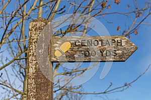 Traditional country wooden public footpath sign to cenotaph monument, with trees in background, Wereth Low, Greater Manchester