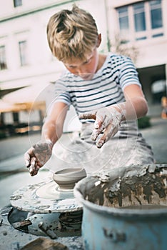 Traditional craft lesson: boy try to make a pottery bowl