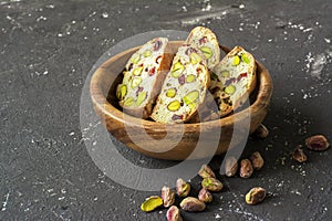 Traditional crispy Italian biscotti or cantuchini crackers with pistachios and dried cranberries in a bowl of olve wood