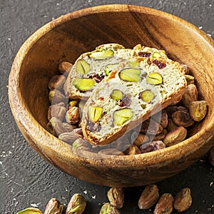 Traditional crispy Italian biscotti or cantuchini crackers with pistachios and dried cranberries in a bowl of olve wood