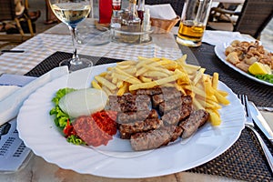 Traditional croatian balkan cevapcici dinner with fies ajvar and onion