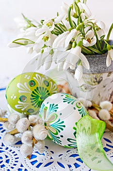 Traditional Czech easter decoration - flowerpot with snowdrops flowers and decorated green eggs with pussycats photo