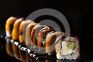 Traditional delicious fresh sushi roll set on a black background with reflection, close up. Sushi roll with rice, cream
