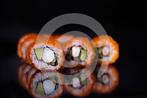 Traditional delicious fresh sushi roll set on a black background with reflection. Sushi roll with rice, cream cheese