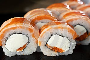 Traditional delicious sushi roll set on a black background with reflection. Sushi roll with rice, cream cheese, salmon