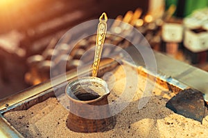 Traditional delicious Turkish dibek coffee being prepared in a copper coffee pot on stove filled with hot sand