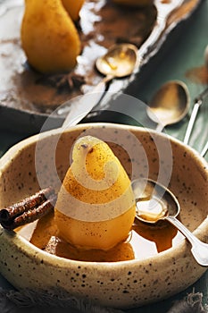 Traditional dessert poached pears with spices in syrup in rustic ceramic bowl. Delicious dessert for holiday.Selective focus