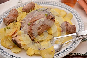 Traditional dish pork shank with potatoes oinon peans in baken on table in restaurant lunch food