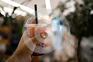 Traditional drink of Taiwan concept. Woman hand holding milk bubble tea with tapioca pearls