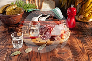 Traditional drink vodka in glasses, with a snack in the form of cold cuts and bacon, cucumbers, preservation. Russian festive