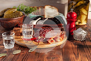 Traditional drink vodka in glasses, with a snack in the form of cold cuts and bacon, cucumbers, preservation. Russian festive