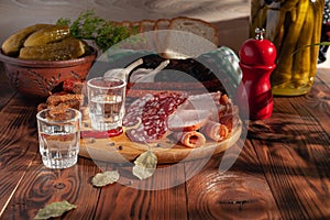 Traditional drink vodka in glasses, with a snack in the form of cold cuts and bacon, cucumbers, preservation. Russian festive