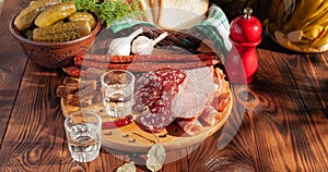 Traditional drink vodka in glasses, with a snack in the form of cold cuts and bacon, cucumbers, preservation. Russian festive