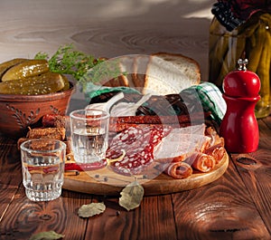 Traditional drink vodka in glasses, with a snack in the form of cold cuts and bacon, cucumbers, preservation. Russian festive