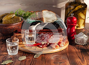 Traditional drink vodka in glasses, with a snack in the form of cold cuts and bacon, cucumbers, preservation. Russian festive